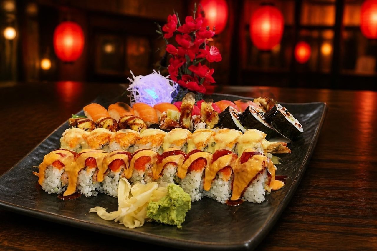 A long plate of rolls topped with salmon and spicy sauce